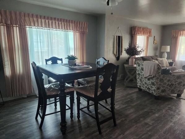 Un coin repas comprenant une table et des chaises en bois, un canapé et une petite table d’appoint avec une lampe.