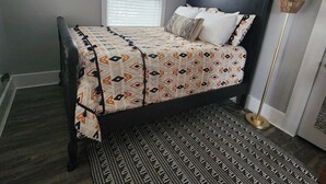 Un dormitorio con una cama, ventana, ventilador de techo y lámpara de pie.