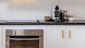 A kitchen with a built-in oven, a coffee maker, and various kitchen utensils on the countertop.