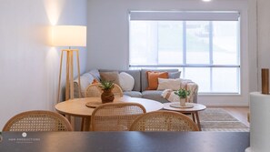 Een moderne woonkamer met een bank, een ronde eettafel en een vloerlamp.
