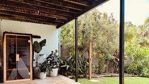 A covered patio area with potted plants and a wooden fence. - Agnes Break | 3BR · Sauna & Walk to Beach (Agnes Water)