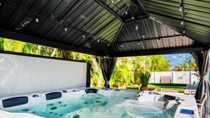 Ett bubbelbad under en överbyggd uteplats med utsikt över trädgården.