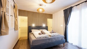 Ein modernes Schlafzimmer mit Bett, Holzpaneelwand und einer Deckenleuchte.