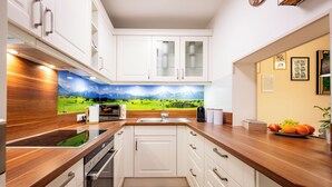 Eine moderne Küche mit weißen Schränken, einer Holzarbeitsplatte und einer aussichtsreichen Wandmalerei als Spritzschutz.