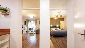 Ein modernes Interieur mit einer Holztreppe, einem Essbereich mit Tisch und Stühlen sowie einem Schlafzimmer mit Bett und Pendelleuchte.