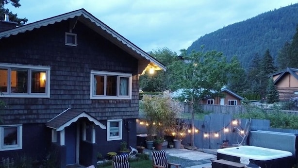 Une maison en bois avec un jardin clôturé, un espace salon extérieur et un jacuzzi.
