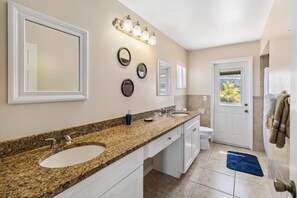 Une salle de bain avec deux lavabos, un meuble-lavabo, un miroir et un espace douche.