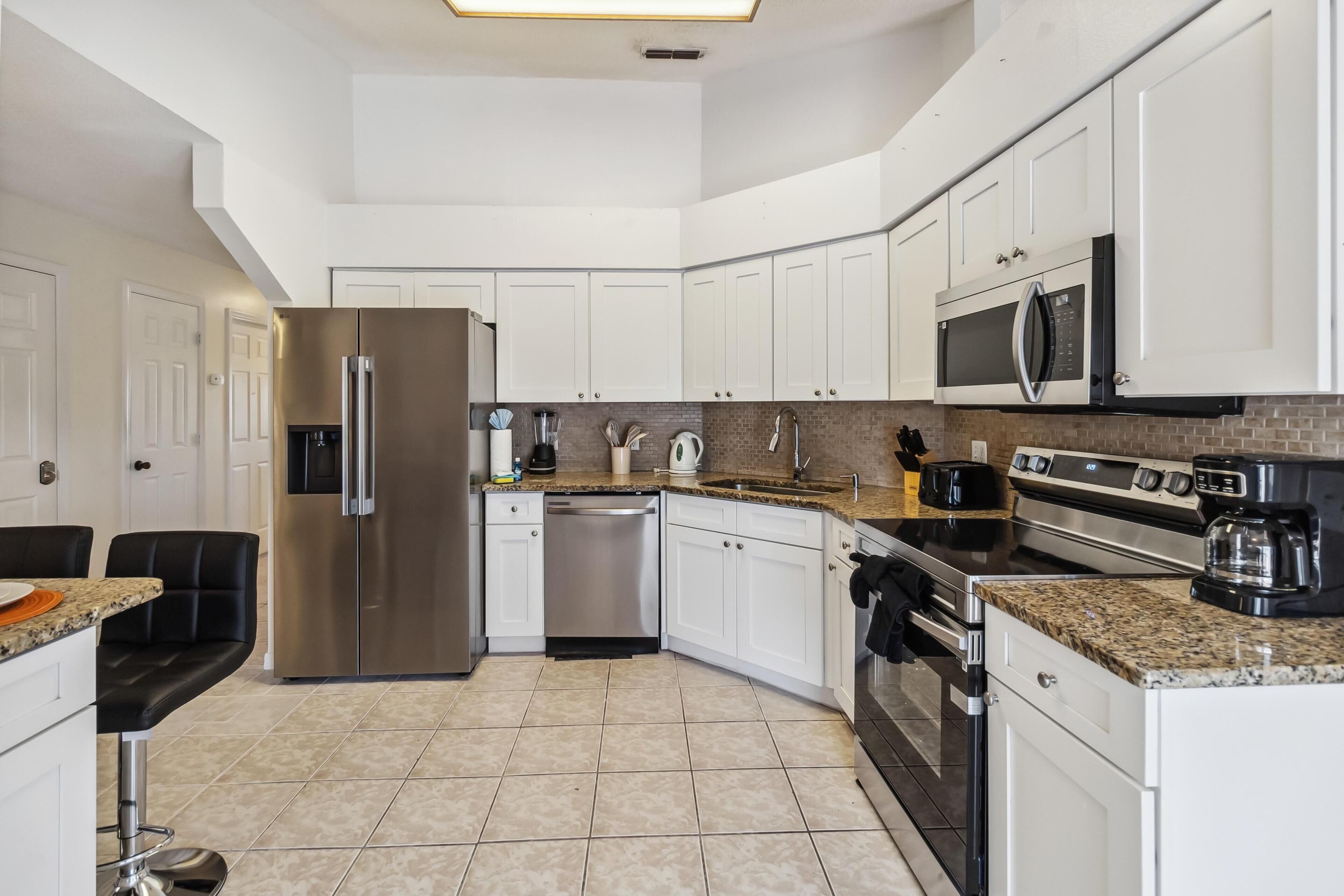A modern kitchen with white cabinets, stainless steel appliances, and granite countertops.