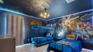 Une chambre à coucher sur le thème de Star Wars, avec des lits superposés, un ventilateur de plafond et une fresque représentant des personnages.