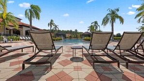 Un espace aménagé au bord de la piscine, avec des chaises longues et un sol carrelé.