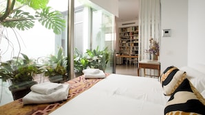 Une chambre moderne avec un grand lit, un mur en verre et une vue sur l’extérieur.