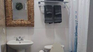 Une salle de bain équipée d’un lavabo, de toilettes et d’un rideau de douche.