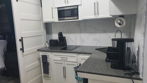 Une cuisine de taille réduite avec des meubles blancs, un four à micro-ondes, un grille-pain et un évier.