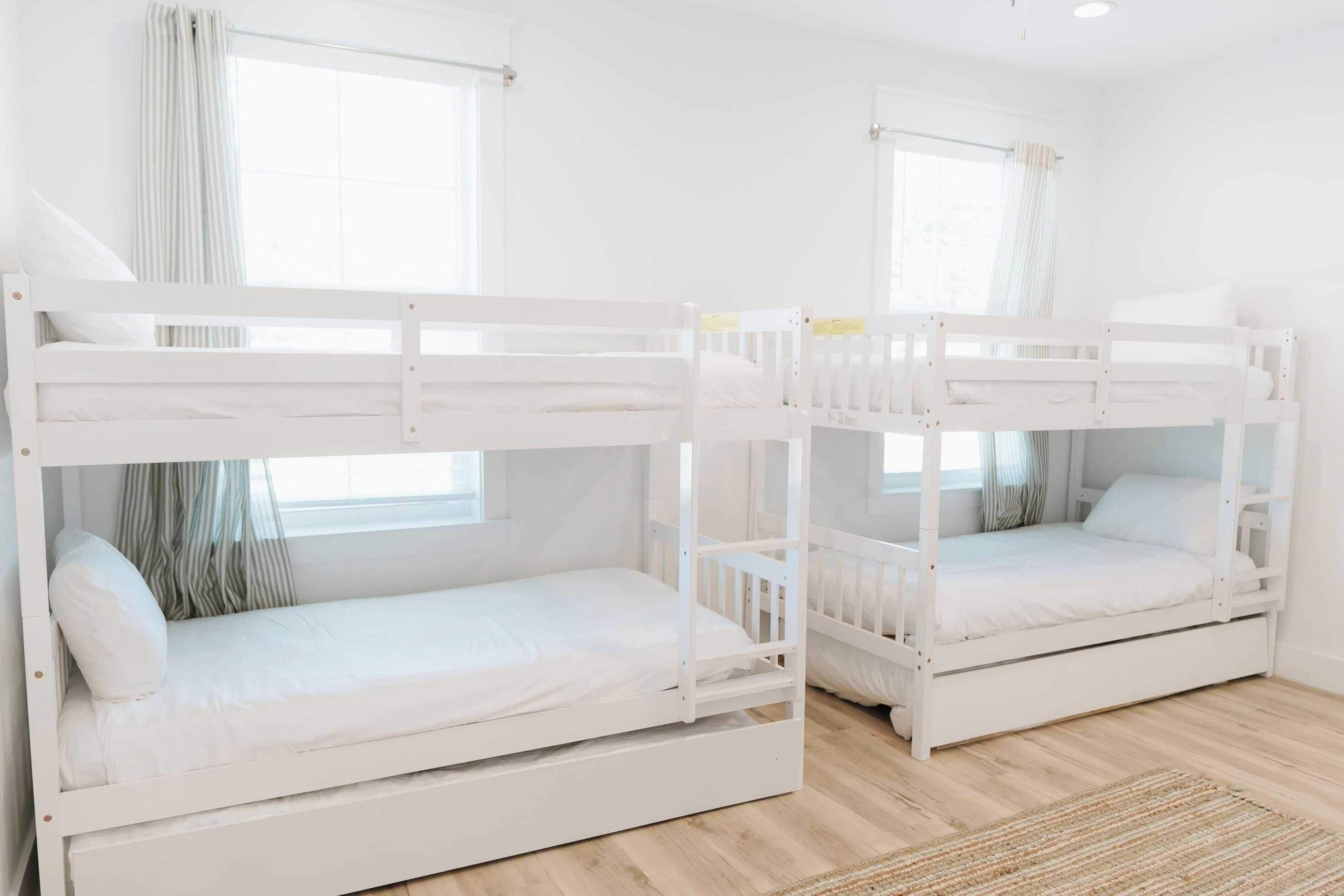 Zwei Etagenbetten in einem Zimmer mit weißen Wänden und Holzboden.