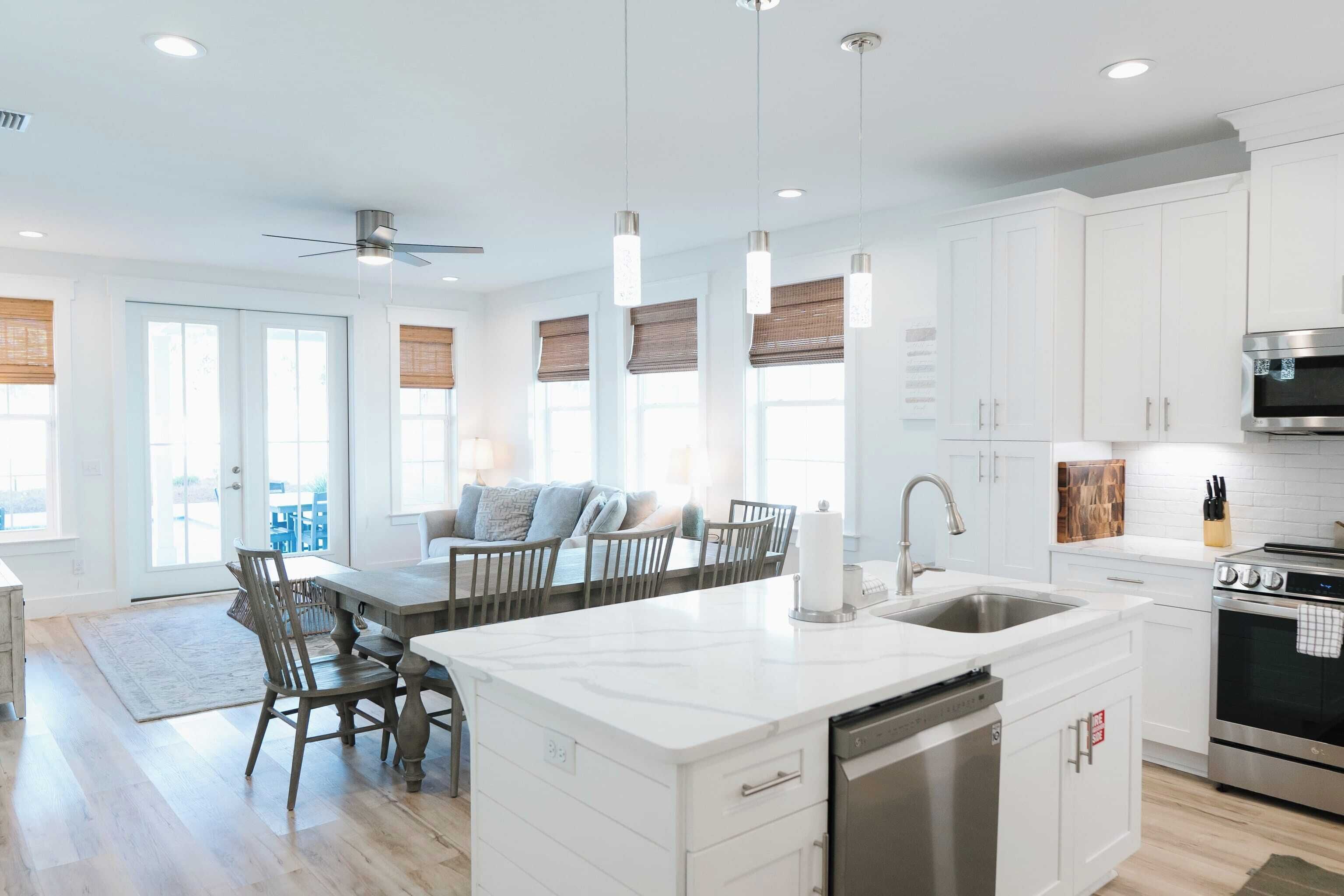 A modern kitchen with white cabinetry, a central island with a sink, and a built-in oven.