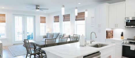 A modern kitchen with white cabinetry, a central island with a sink, and a built-in oven.