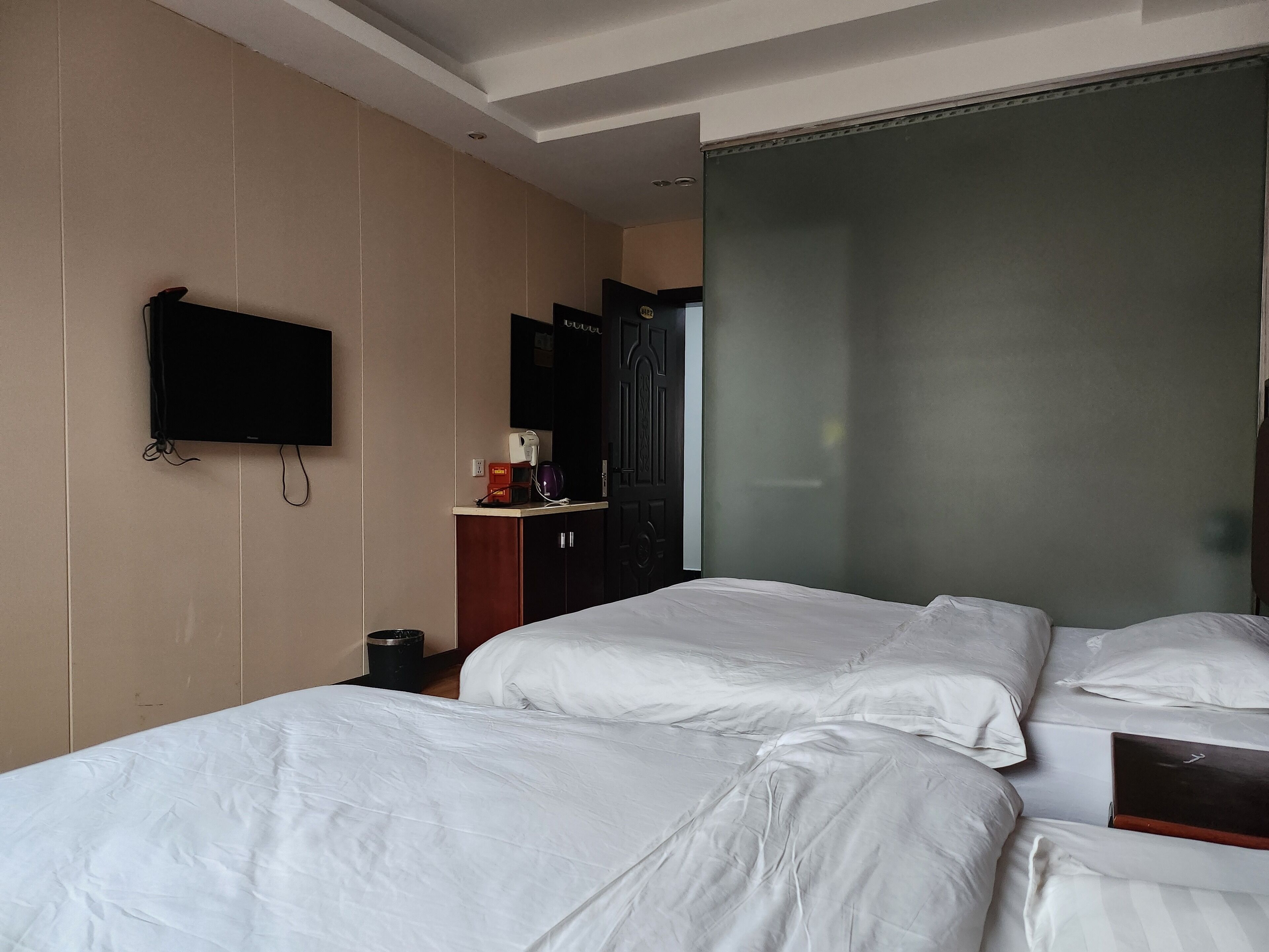 A hotel room with two beds, a television, a coffee machine, and a wardrobe.