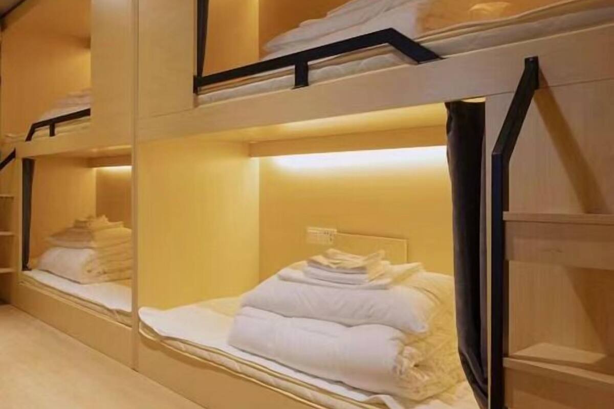 Habitación de hotel con literas, cada una con cabecero y estante superior.