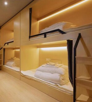 Een hotelkamer met stapelbedden, elk voorzien van een hoofdeinde en een plank erboven.