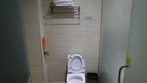 A small, tiled bathroom with a white toilet, a towel rack, and a trash bin. - Biancheng International Youth Hostel (Xiangxi)