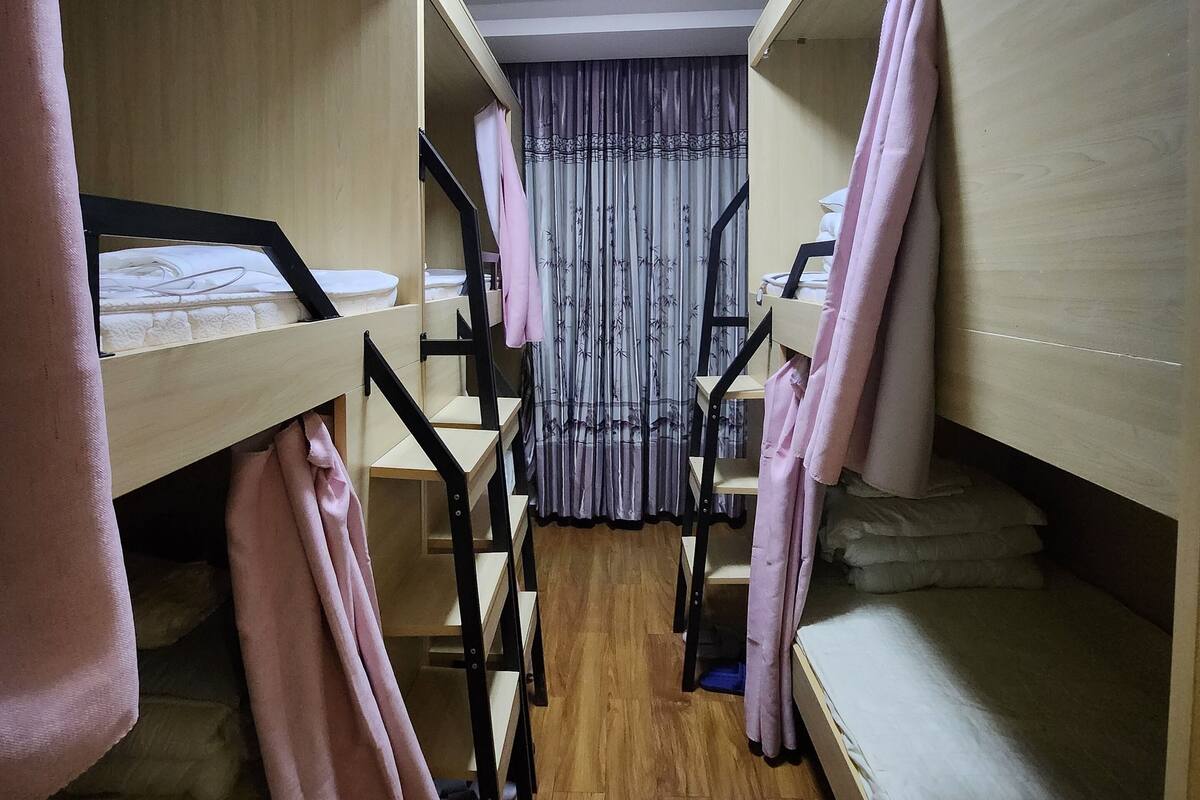Un dormitorio con literas, suelo de madera y una lámpara en el techo.