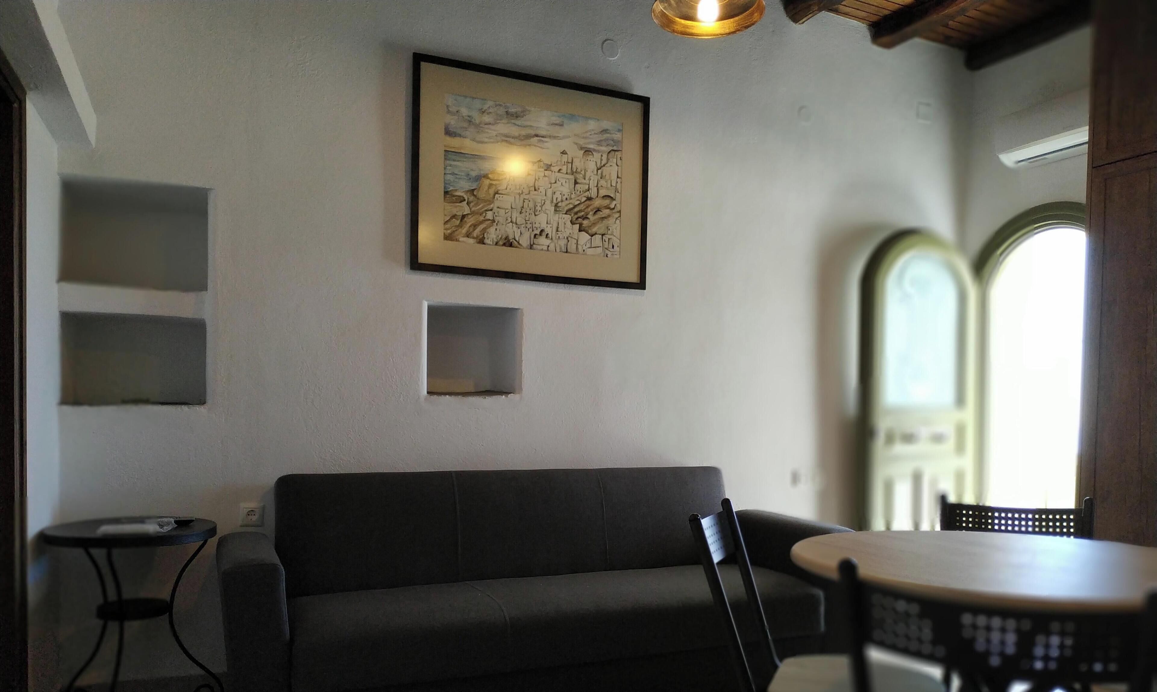 Ein Zimmer mit einer Couch, einem kleinen Tisch und einem gerahmten Bild an der Wand.