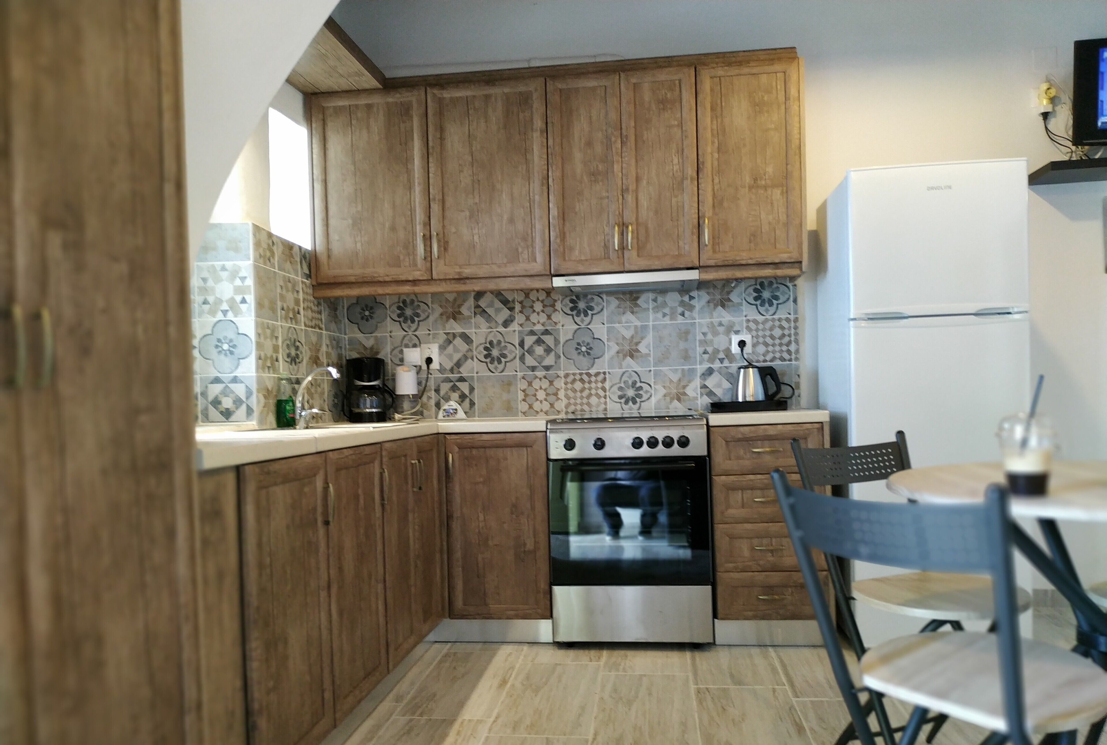 Eine Küche mit Holzschränken, einem Edelstahlbackofen und einem weißen Kühlschrank.