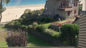 A stone building with a balcony, a beach, and a clear sky. - Apartment 'Newport Vue Mer' with Sea View, Private Terrace and Wi-Fi (Saint-Cast-le-Guildo)