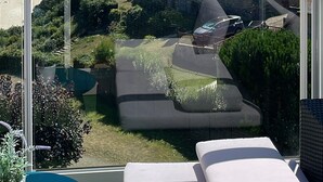 A balcony with a view of a beach, a stone building, and a car parked in the driveway. - Apartment 'Newport Vue Mer' with Sea View, Private Terrace and Wi-Fi (Saint-Cast-le-Guildo)