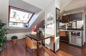 A compact kitchen with modern appliances, a dining area with a table and chairs, and a skylight window.