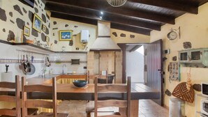 A rustic kitchen with wooden furniture, stone walls, and a stone fireplace.