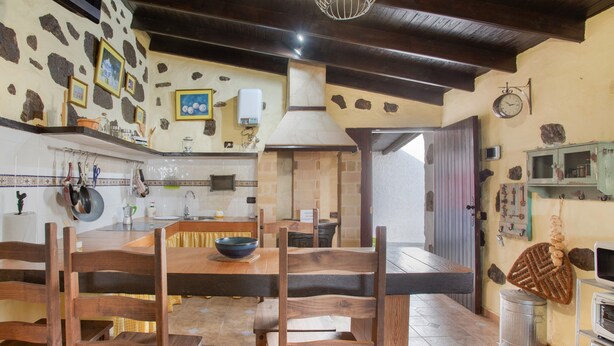 Une cuisine rustique, avec des meubles en bois, des murs en pierre et une cheminée en pierre.
