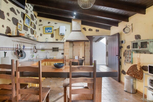 Una cocina rústica con muebles de madera, paredes de piedra y una chimenea de piedra.