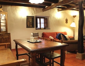 A wooden dining table with chairs, a sofa, a lamp, and a painting on the wall.