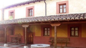 A courtyard with a stone well, wooden benches, and a tiled roof.