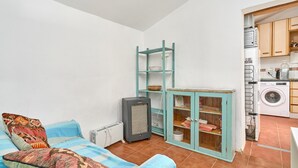 A compact living space with a sofa, a small cabinet, a radiator, and a washing machine. - Country House 'The Tack Room' with Mountain View, Shared Pool and Wi-Fi (Rubite)