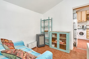 A compact living space with a sofa, a small cabinet, a radiator, and a washing machine.
