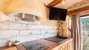 A kitchen with a stone wall, a flat-screen TV, a sink, and a window with a view. - Apartment 'Duende' with Mountain View, Balcony and Air Conditioning (Olba)