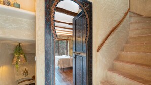 A narrow hallway with a wooden staircase, a bed in the distance, and a decorative door. - Apartment 'Duende' with Mountain View, Balcony and Air Conditioning (Olba)