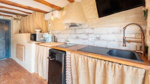 A kitchen with a wooden countertop, a sink, a black dishwasher, a microwave, and a television mounted on the wall. - Apartment 'Duende' with Mountain View, Balcony and Air Conditioning (Olba)