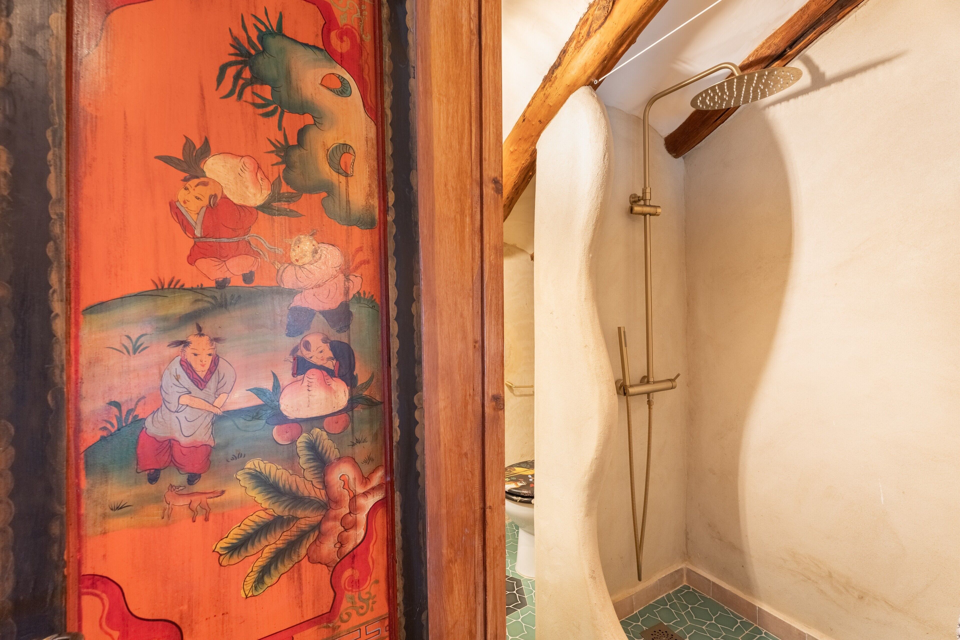 Ein traditioneller japanischer Raum mit einer Schiebetür, verziert mit einem farbenfrohen Wandgemälde, einem kleinen Waschbecken und einer Holzbalkendecke.