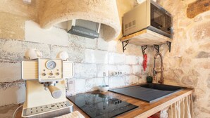 Eine Küche mit Kaffeemaschine, Mikrowelle, Spüle und einer Steinwand.