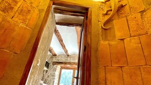 Ein Korridor mit Steinsäulen und einer Holztür, die in einen anderen Raum führt.
