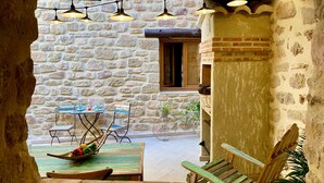 Un muro in pietra rustica, un tavolo di legno con sedie e lampade a sospensione.