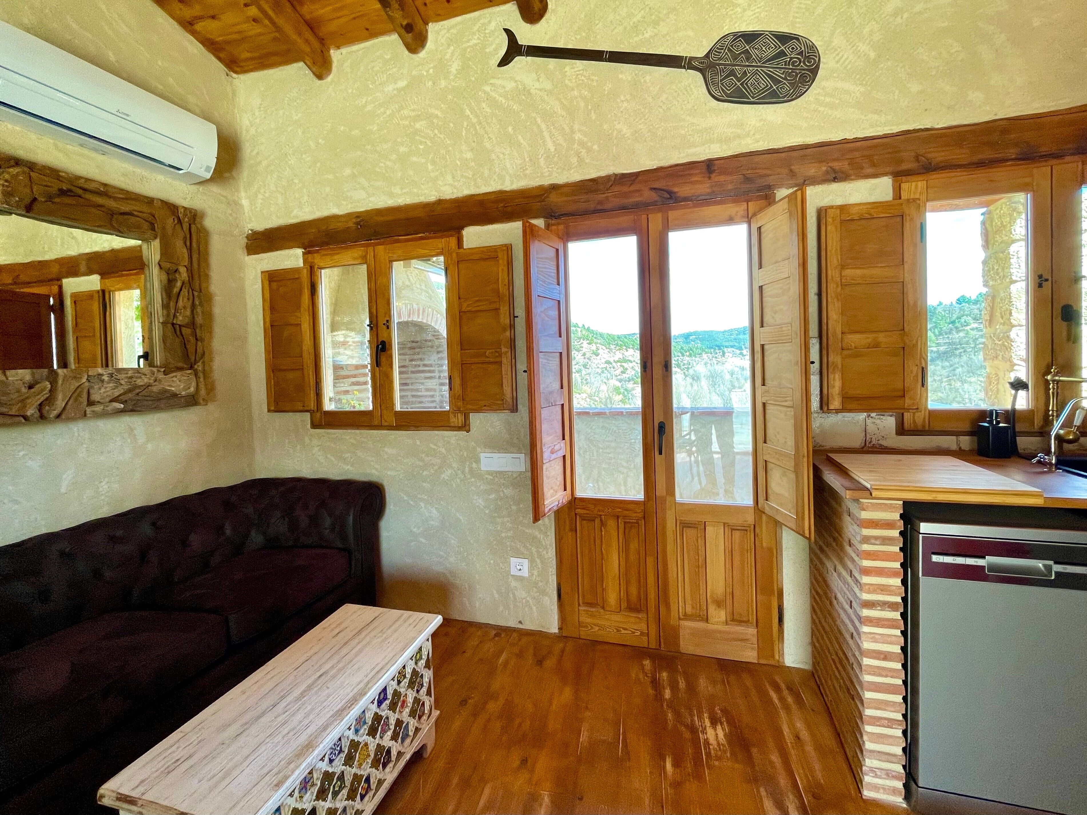 Une cuisine rustique avec des meubles en bois, un lave-vaisselle encastré et une vue sur l’extérieur.
