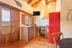 A kitchen with wooden cabinets, a red refrigerator, a dishwasher, and a wooden chair.