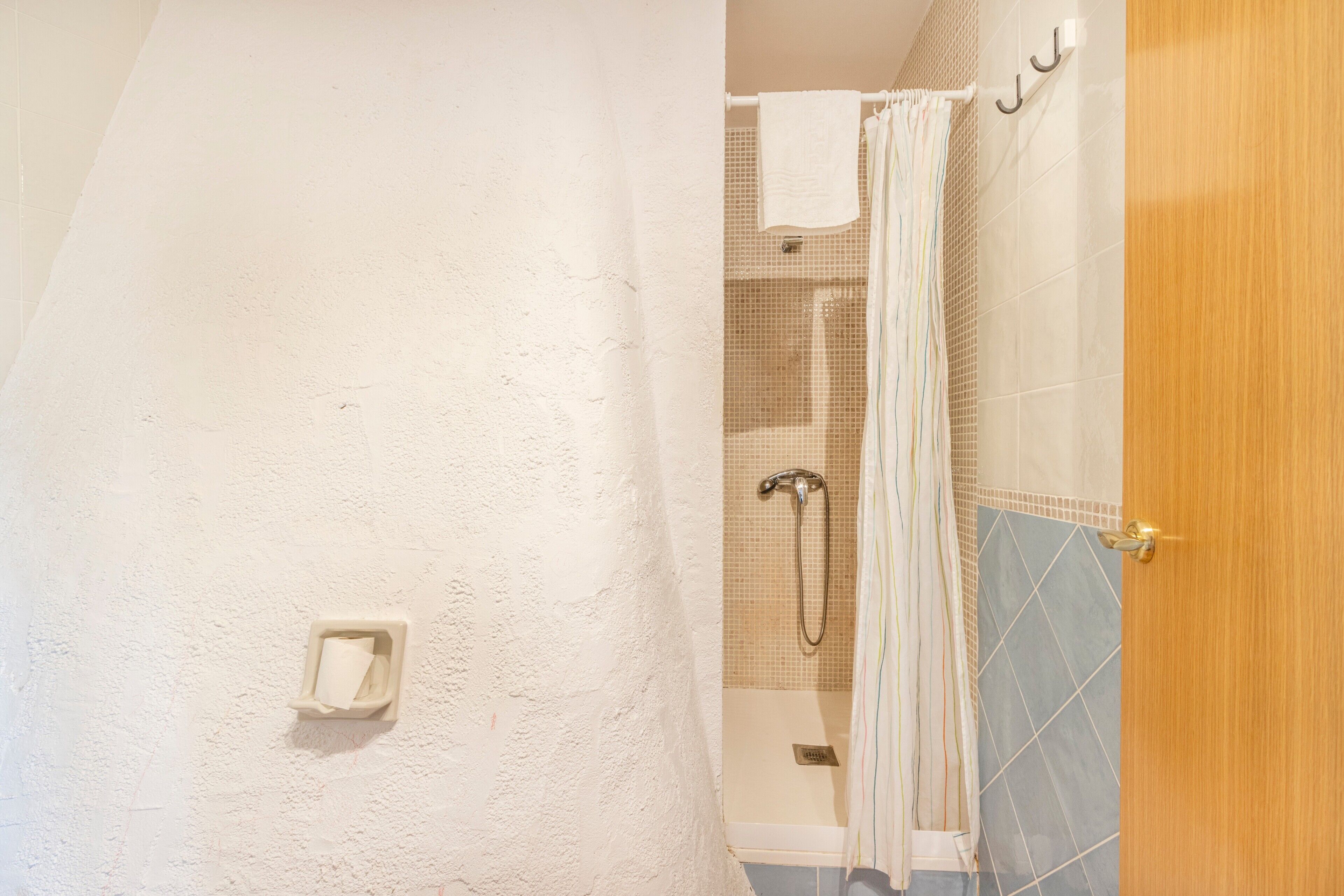 A bathroom with a shower, a towel rack, and a door.