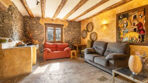 A rustic interior with stone walls, wooden beams, a stone fireplace, and a traditional painting. - Apartment 'Las Planeras' with Mountain Views, Shared Pool and Wi-Fi (Graus)