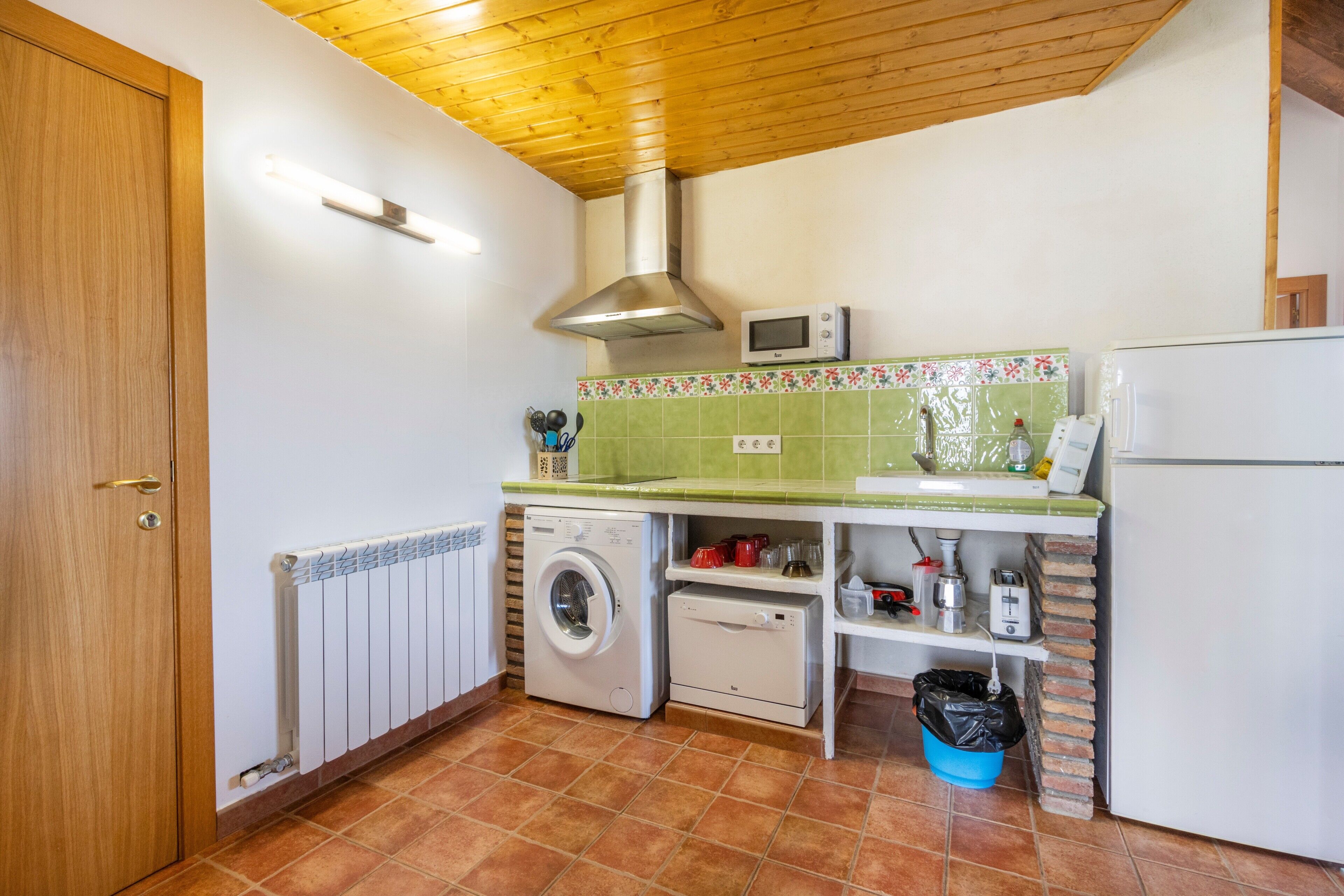Una cocina compacta equipada con lavadora, microondas y refrigerador.