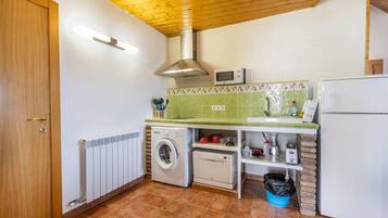 Una cocina compacta equipada con lavadora, microondas y refrigerador.